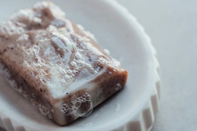 Detailed close-up of a handmade organic soap bar with bubbles on a dish, highlighting its texture and the difference between a hot process soap and a cold process soap